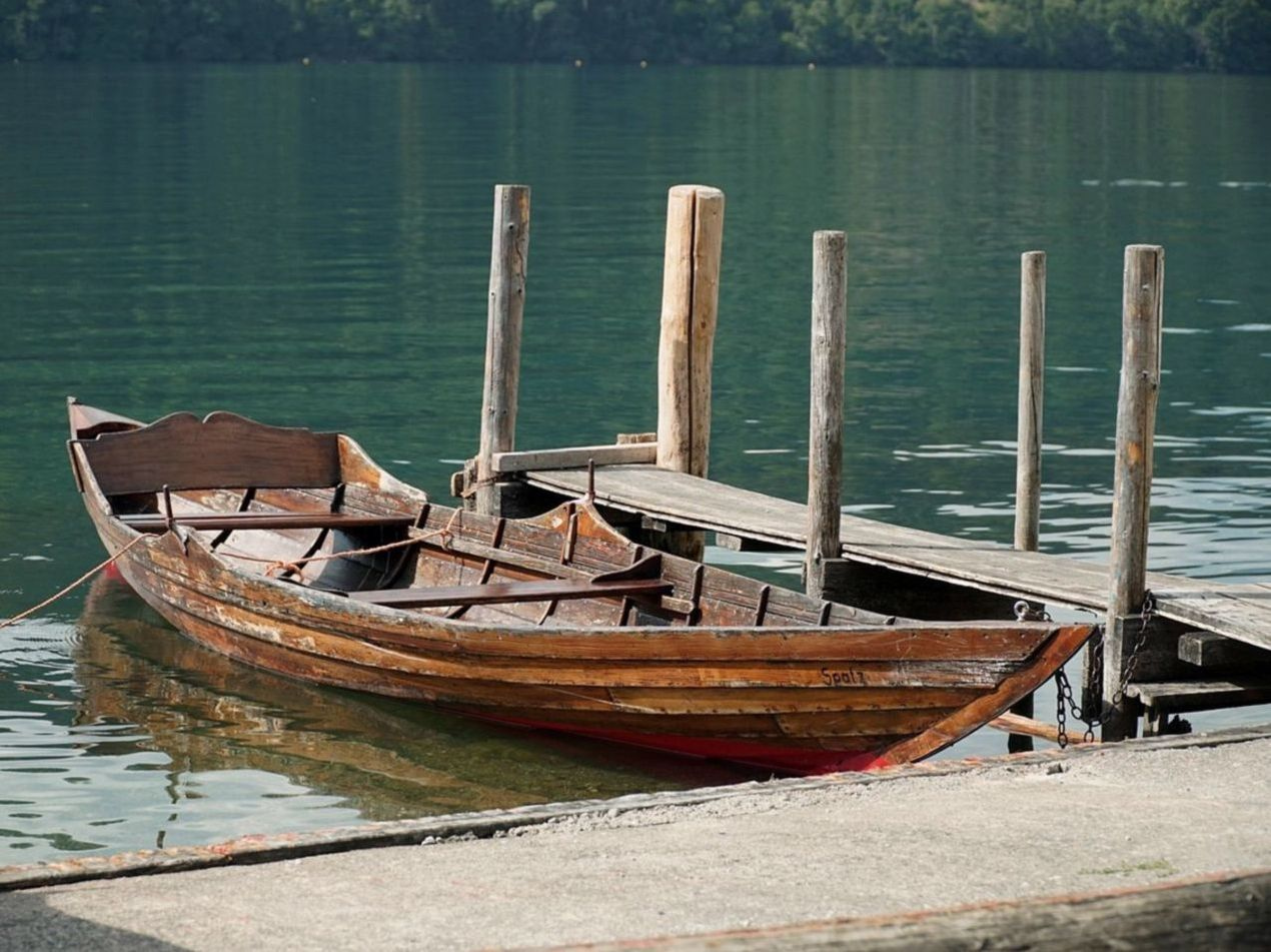 Classic rowing boat resting at a wooden dock with calm water behind